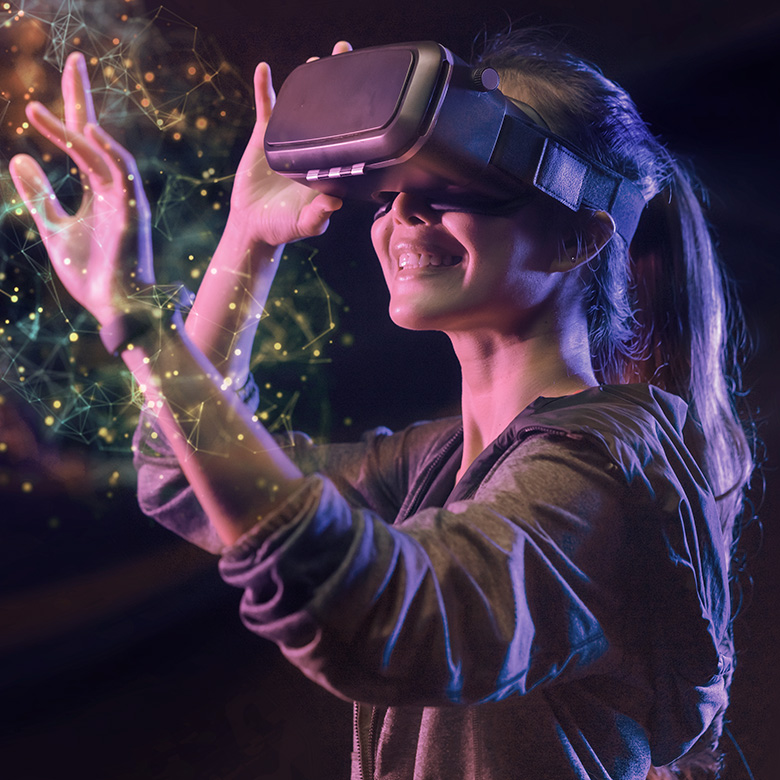 Eine Frau trägt eine virtual Reality-Brille. Vor ihr wird die virtuelle Welt mit Hilfe von Partikeln dargestellt.