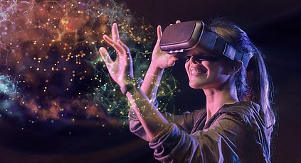 Eine Frau hantiert mit virtuellen Partikeln, die durch die Virtual Reality Brille sichtbar werden.