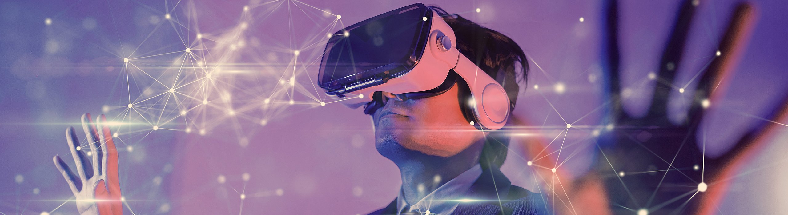 Ein Mann mit einer Virtual Reality Brille der seiner Kreativität in der virtuellen Welt freien lauf lässt, indem er vernetzte Würfel mit den Händen verschiebt.