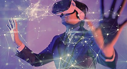 Ein Mann mit einer Virtual Reality Brille der seiner Kreativität in der virtuellen Welt freien lauf lässt, indem er vernetzte Würfel mit den Händen verschiebt.